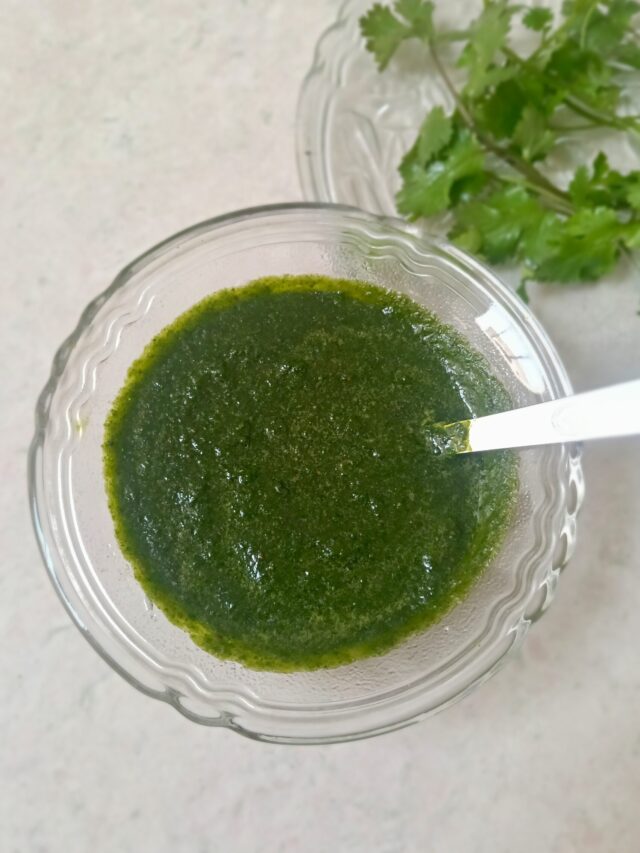 Green chutney filled in a glass bowl with a spoon