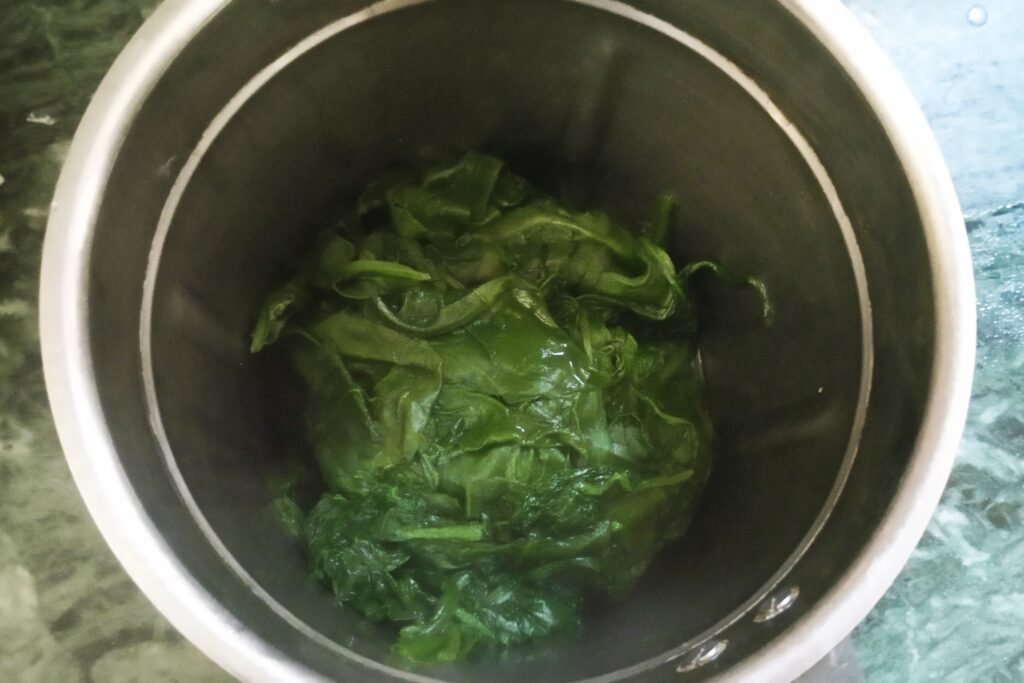 Adding boiled spinach leaves in a blender