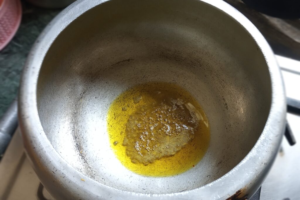Heating oil and cumin seeds in pressure cooker