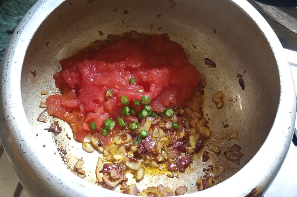 Adding tomato puree and green chilies