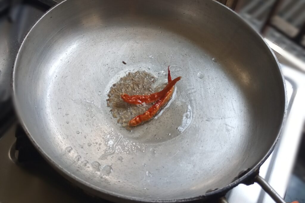 Cumin seeds and dried red chilies are crackling