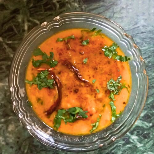 Hot dal tadka recipe topped with tempering and herbs