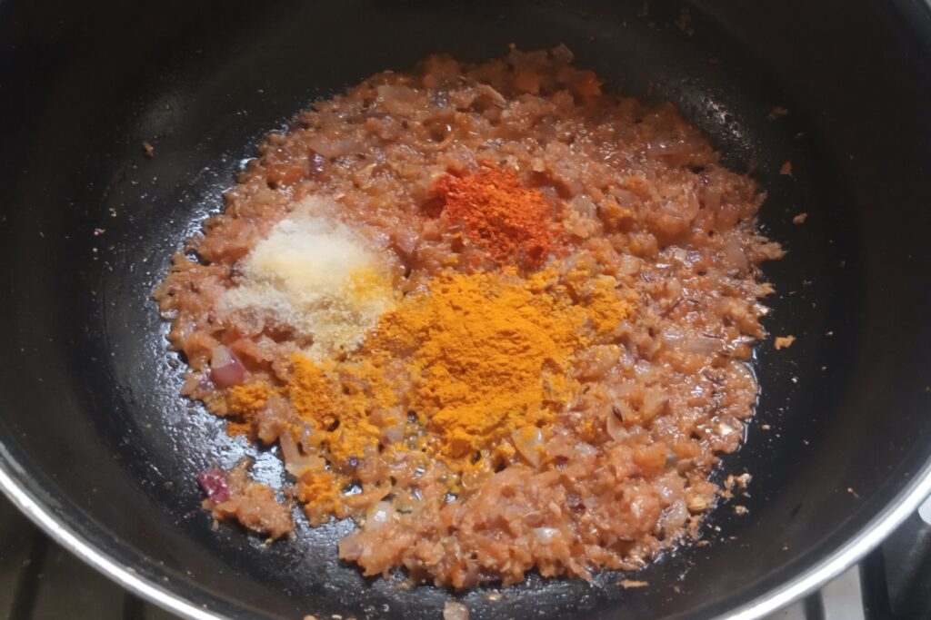 adding spices in the cooking tomatoes