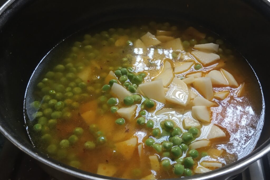 adding water to the potato and peas mixture