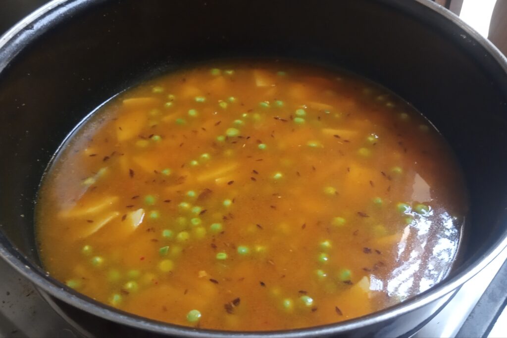 mixing potatoes and peas with water for potato peas curry