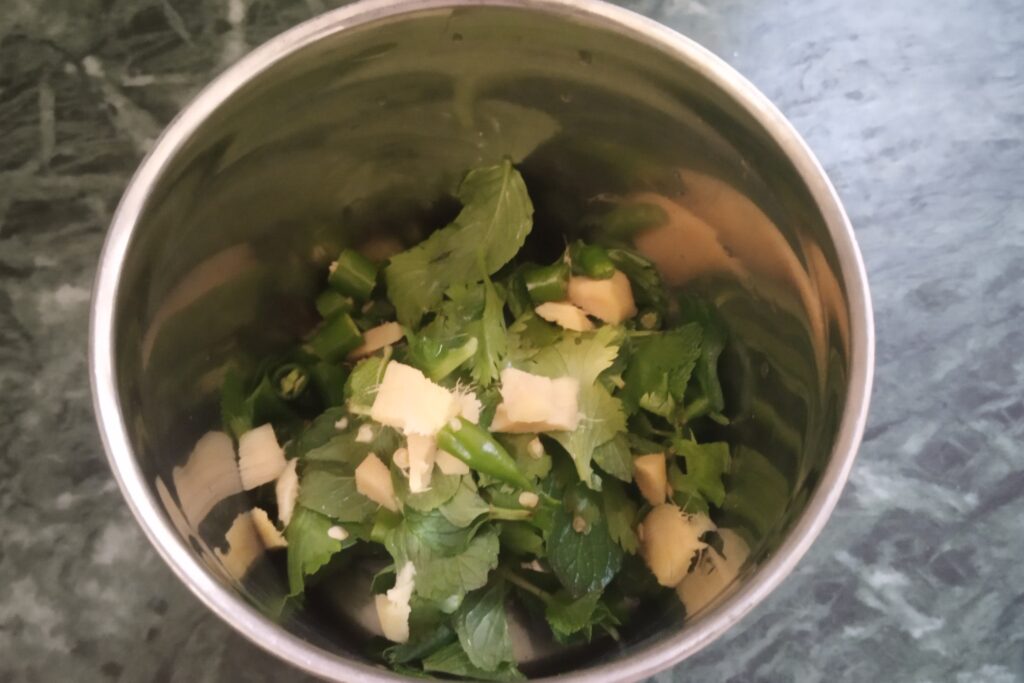 adding leaves green chilies and ginger in a blender
