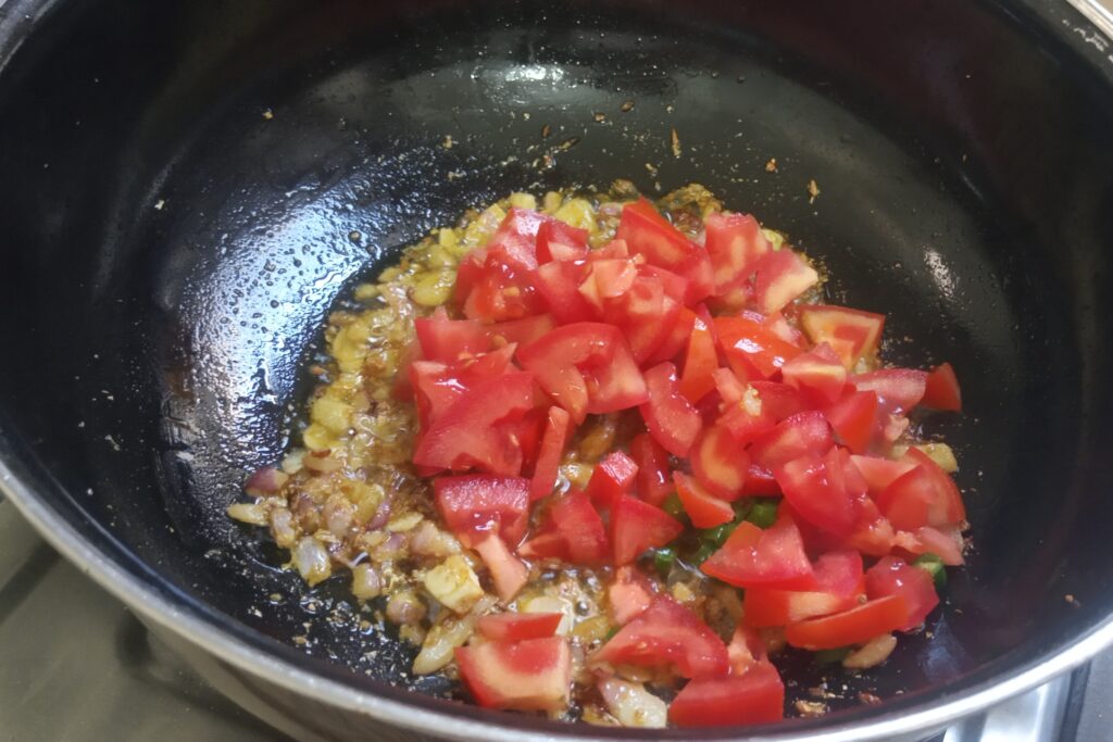 adding chopped tomatoes and green chilies