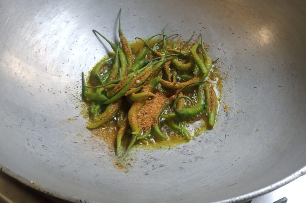 adding filled green chilies in heated oil