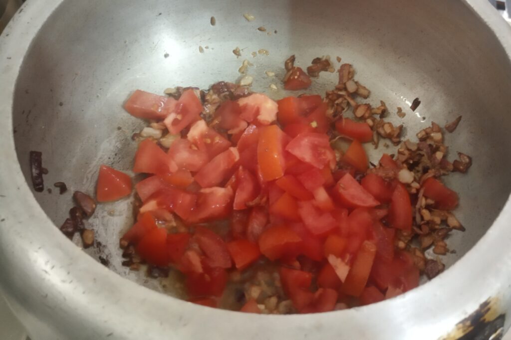 adding chopped tomato to saute
