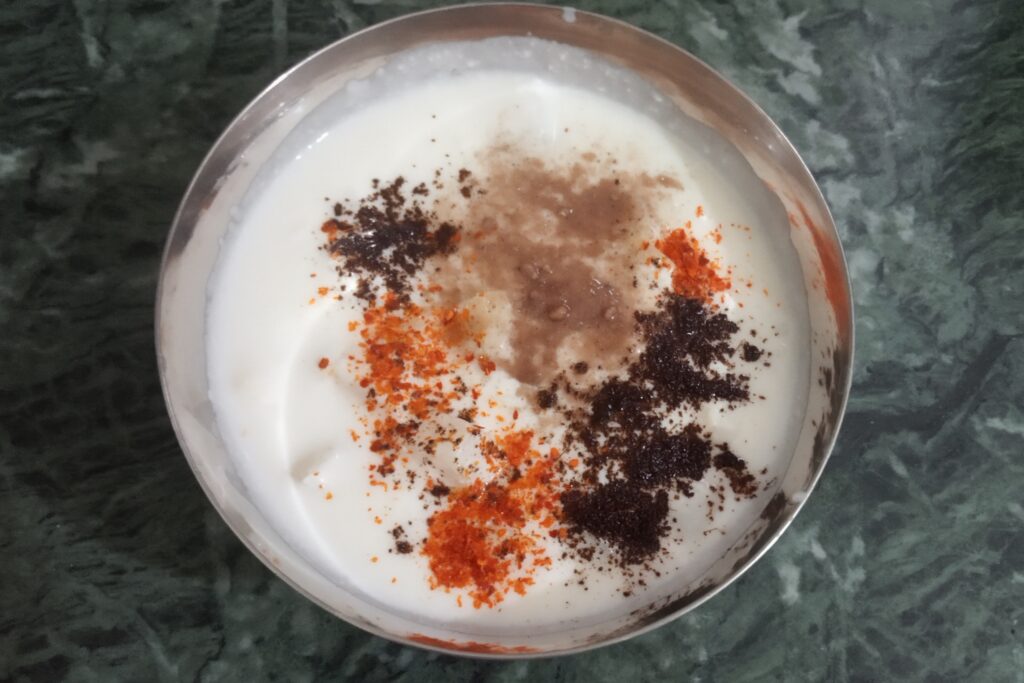 adding spices to potato raita