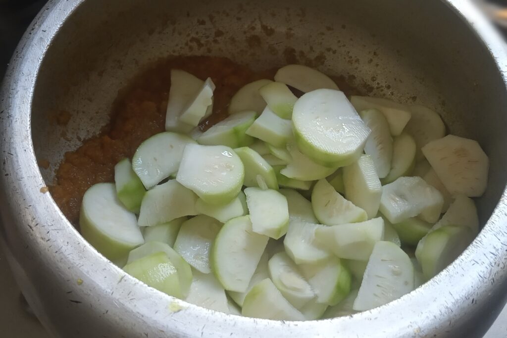 adding sliced round gourds in the spices