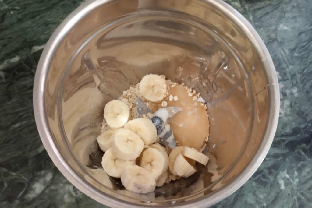 adding banana oats and honey to a blender