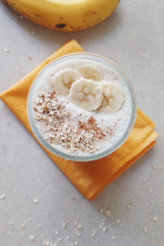 tops shot of chilled oats banana smoothie garnish with cinnamon powder
