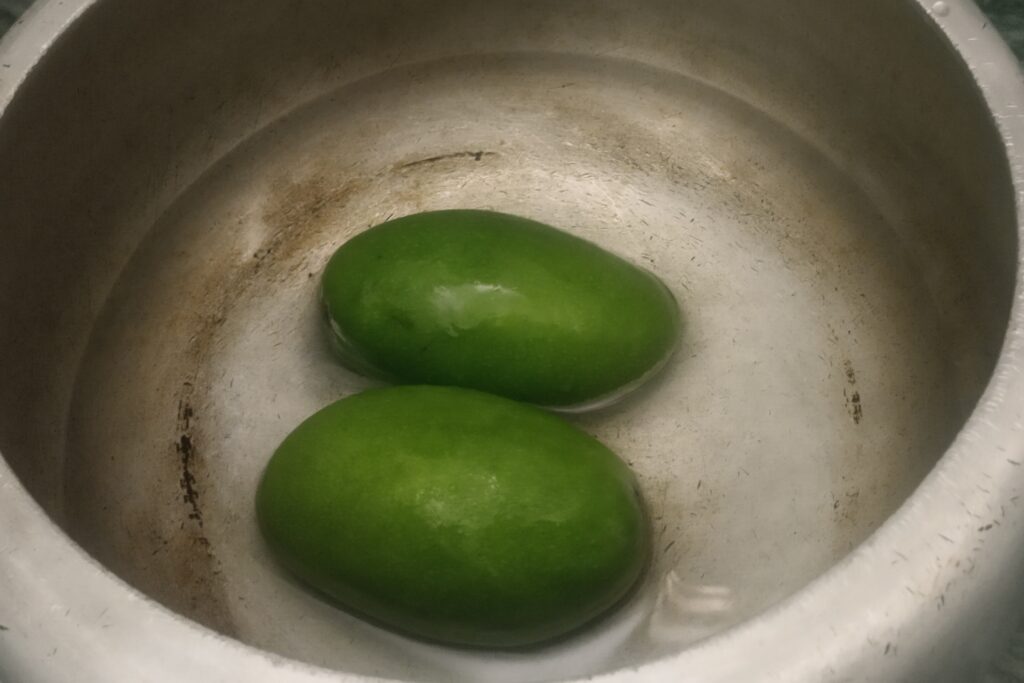 raw mangoes with water in a pressure cooker
