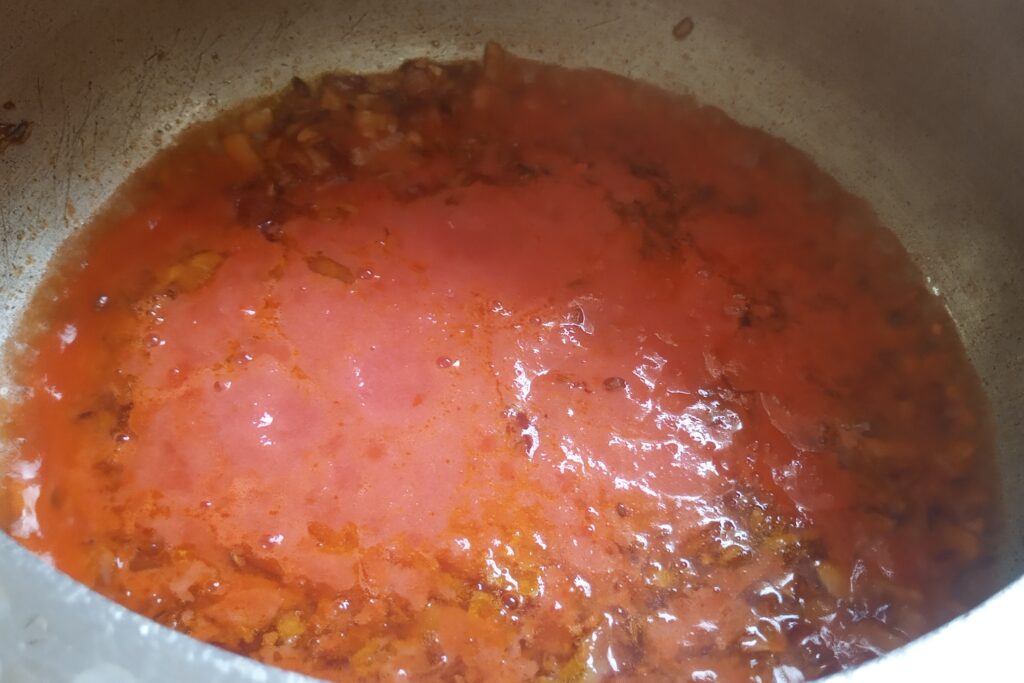 adding tomato puree into sauteed onion