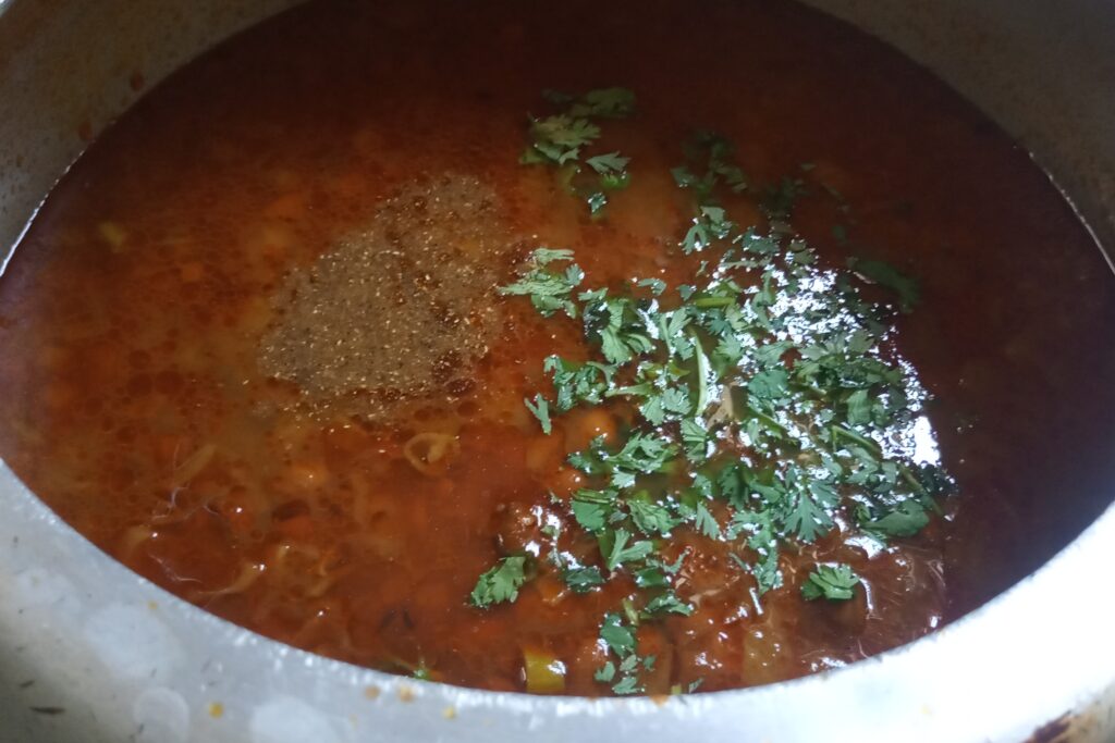adding garam masala and herbs to cooked curry