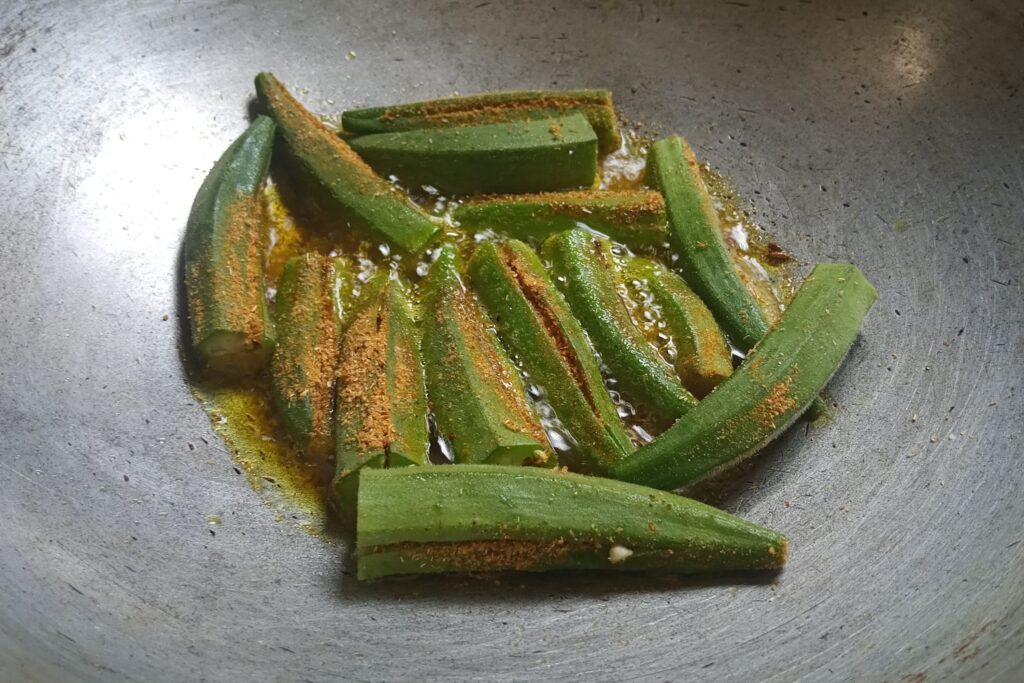 adding stuffed okra in the sizzled cumin seeds