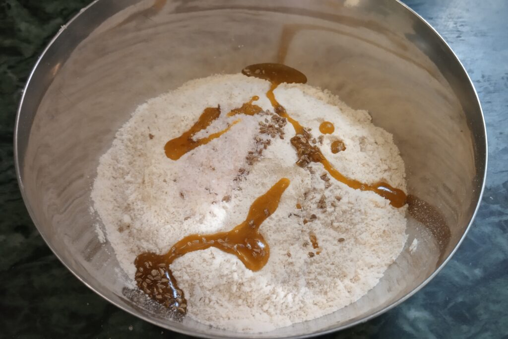 flour oil carrom seeds in a mixing bowl