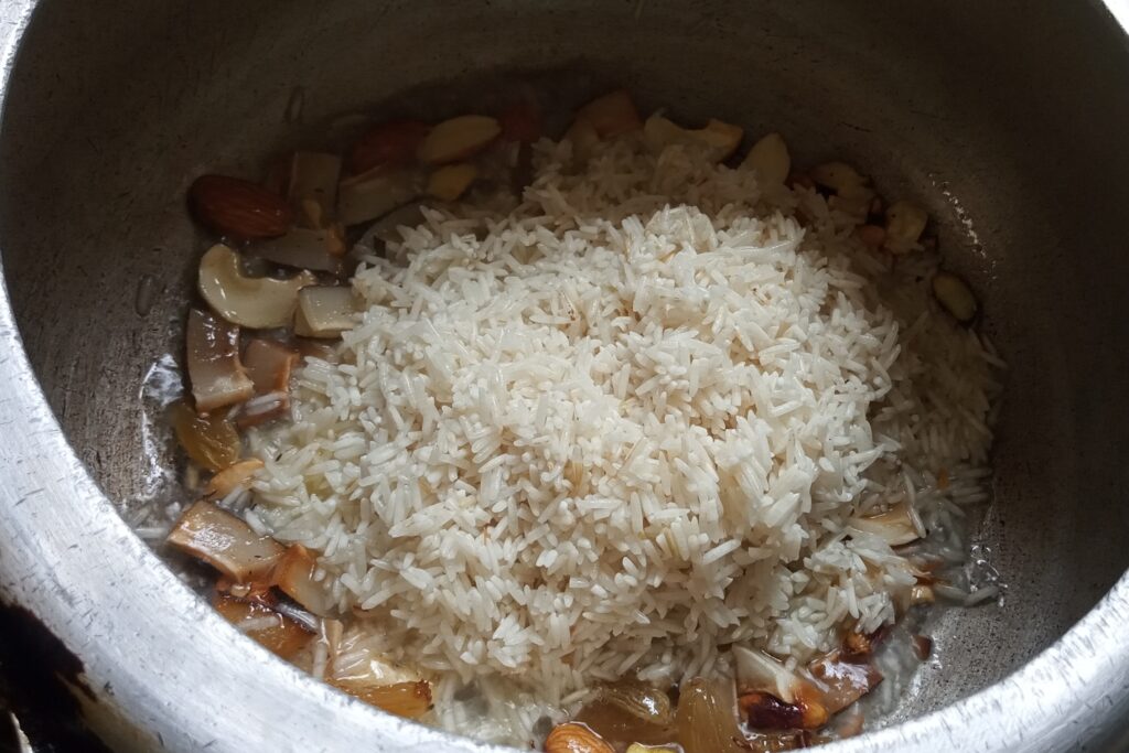 adding soaked rice in the roasted nuts