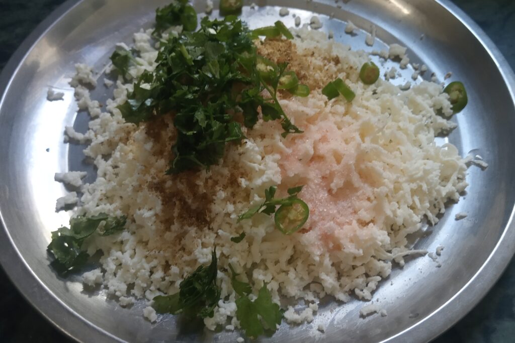adding spices and herbs to the grated paneer