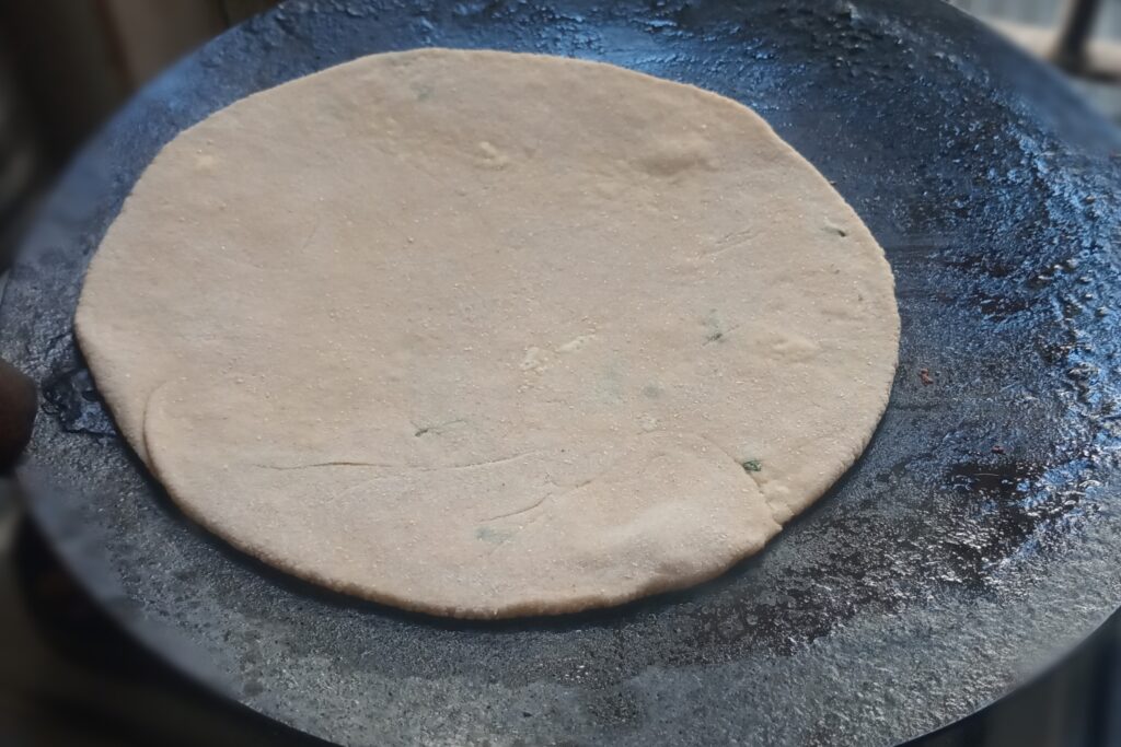 adding rolled paneer paratha on the tawa