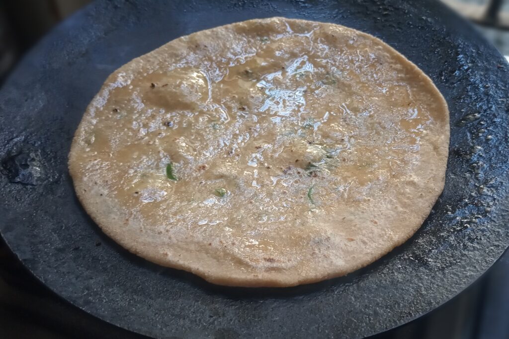 applying ghee on the paneer paratha