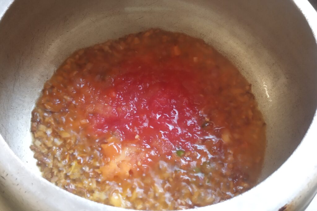 adding tomato puree in onions