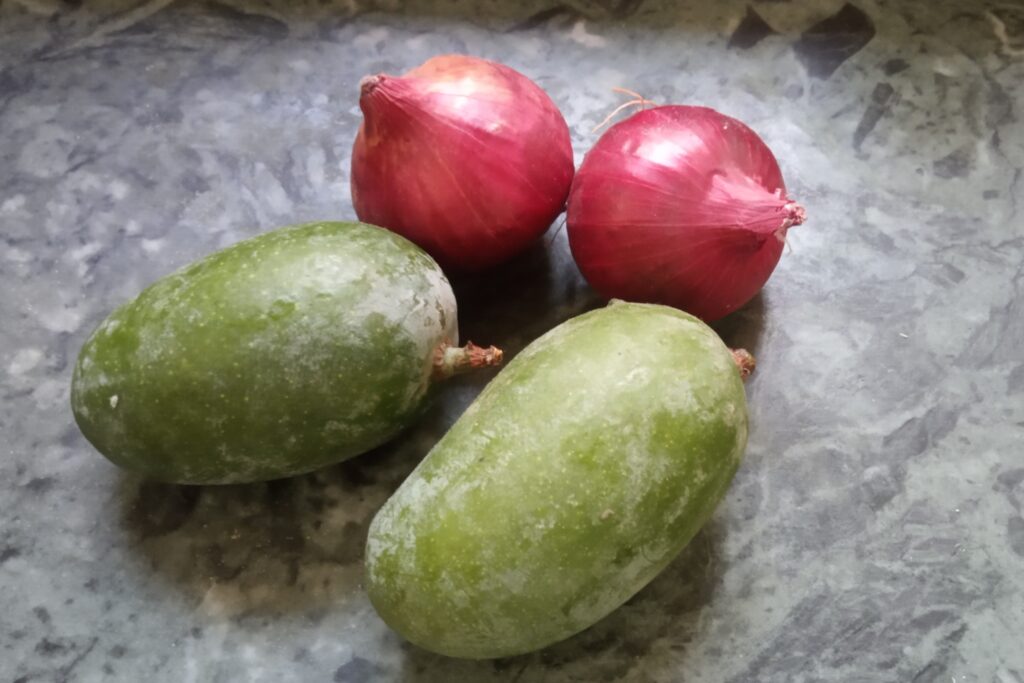raw mangoes and red onion on marble
