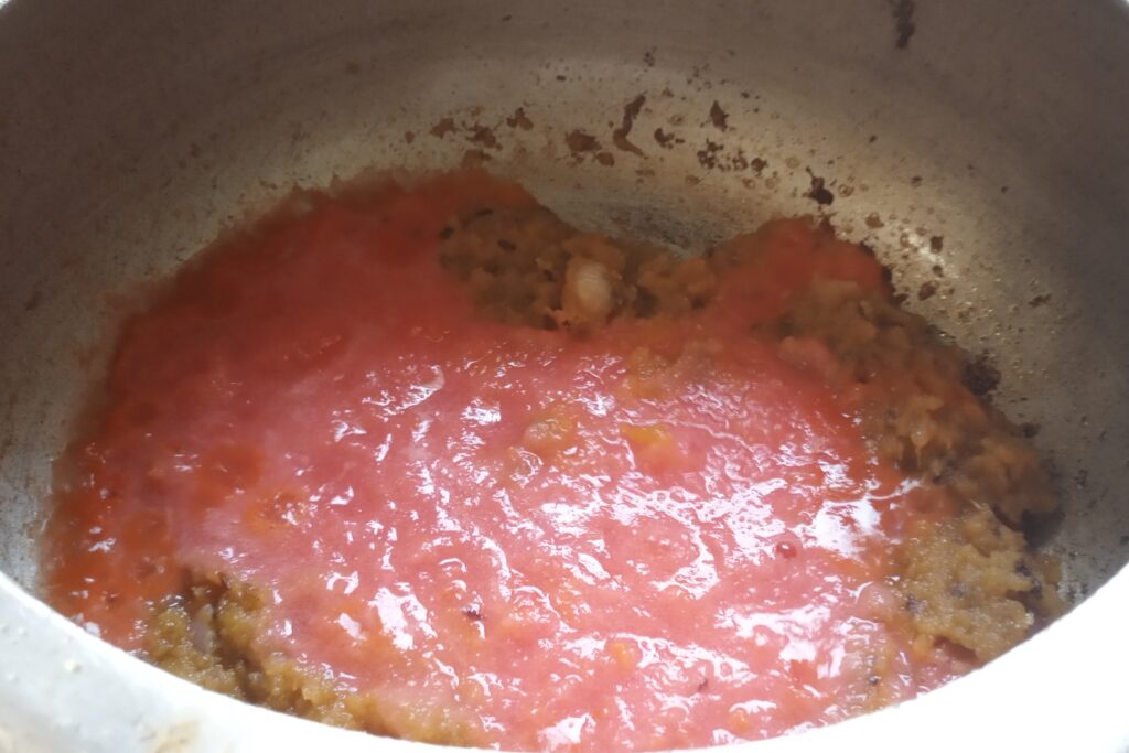 Adding tomato puree in onions